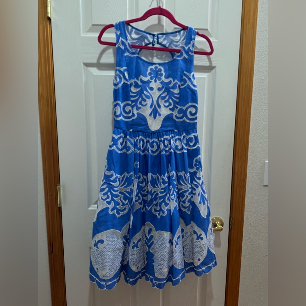 Blue dress with white designs and details.